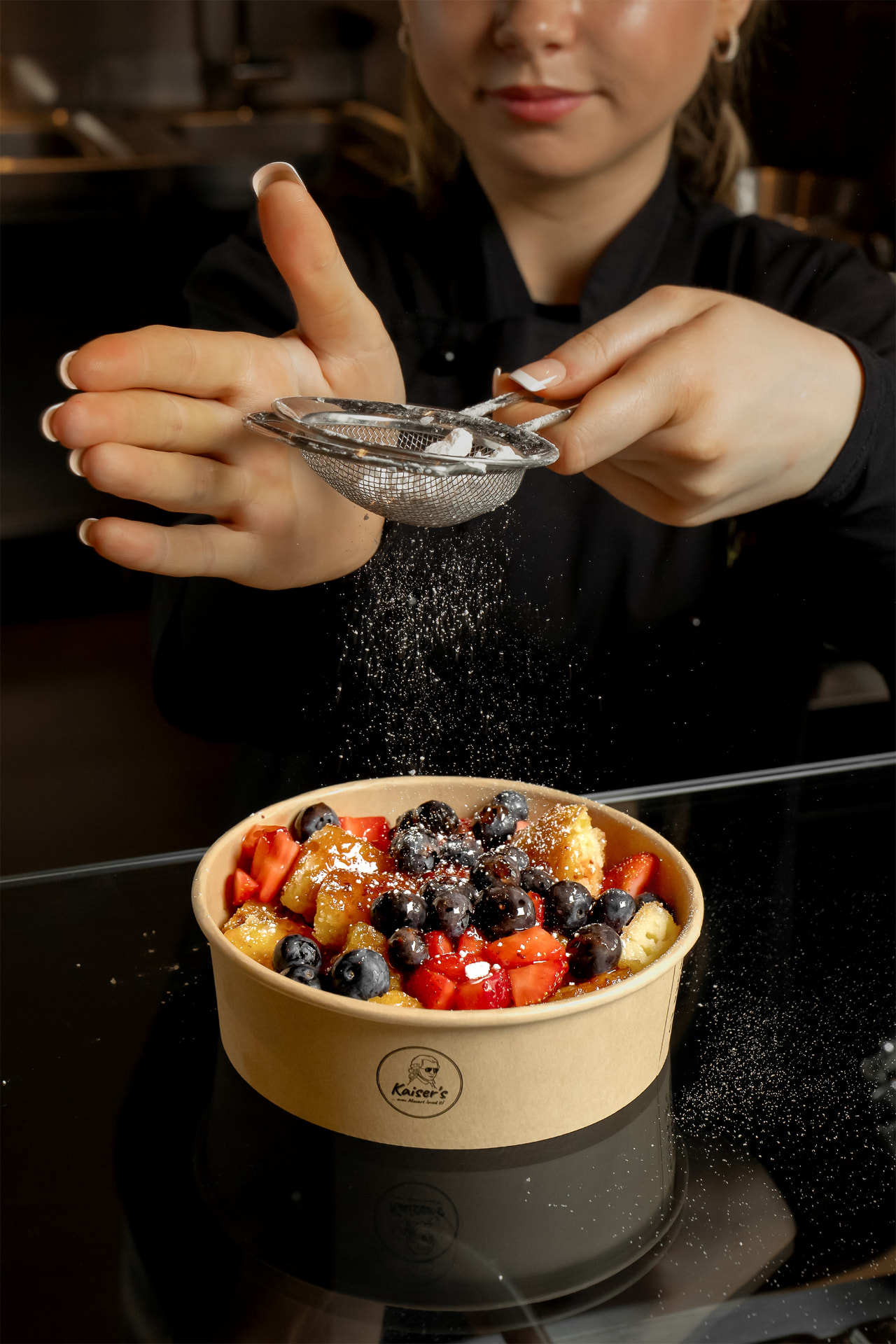 Kaiser's team member finishing strawberry-blueberry Kaiser'schmarrn with powdered sugar